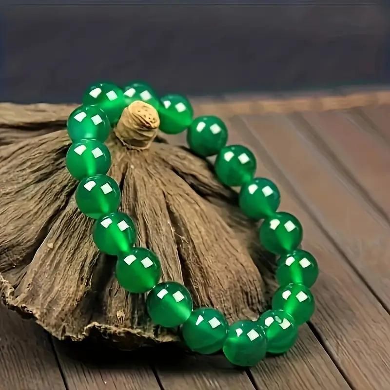 Green beaded bracelet on a piece of wood with a dark background