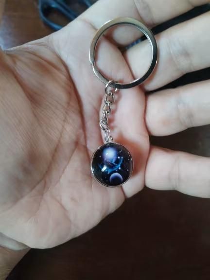 Keychain with a celestial design held in a hand against a dark background
