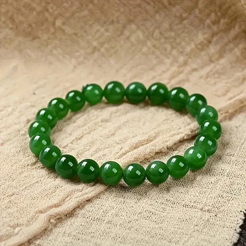 Green beaded bracelet on a textured beige fabric background